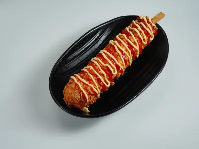 Korean corn dog drizzled with ketchup and mustard on a black plate